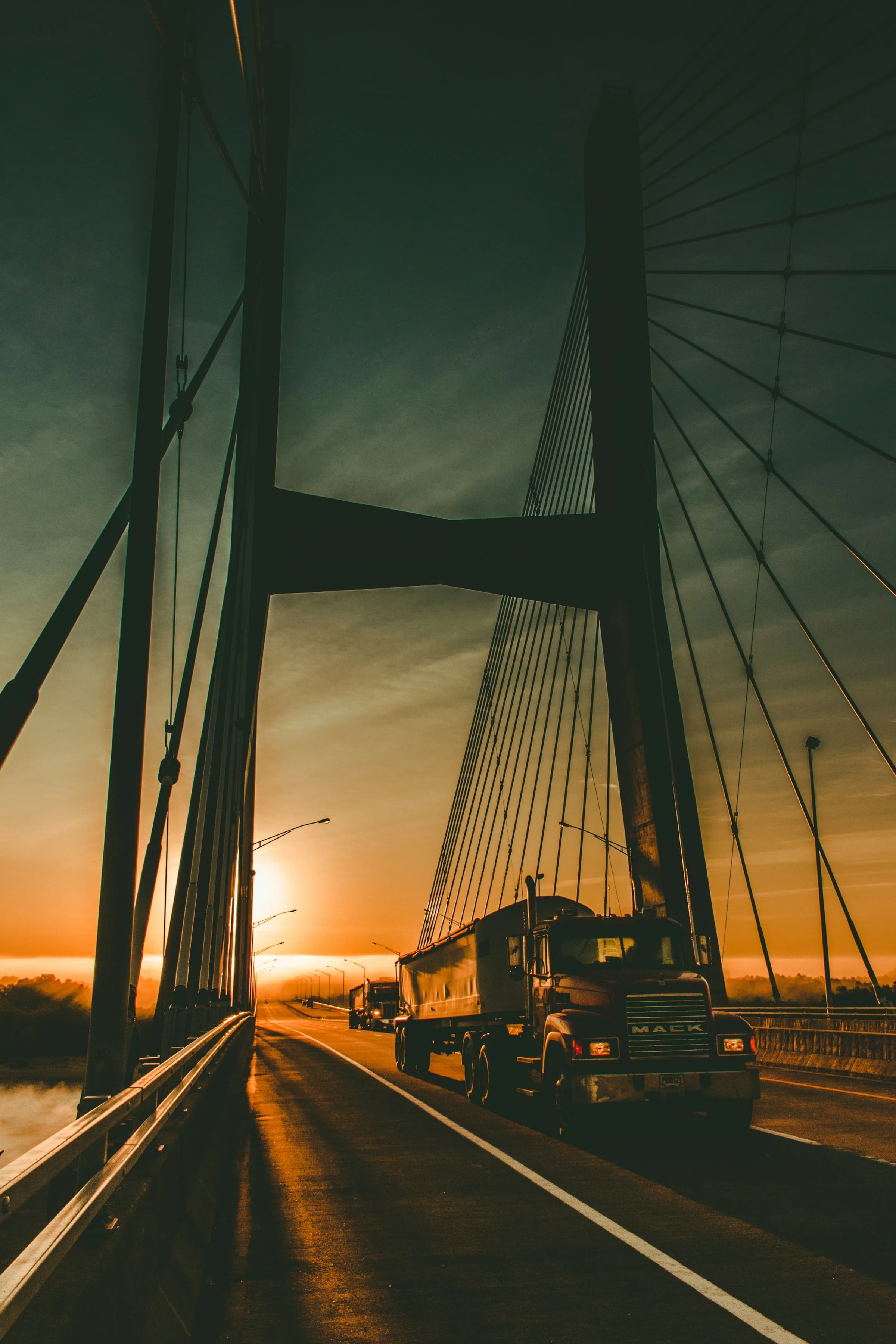 Freight truck crossing a cable-stayed bridge at sunrise
